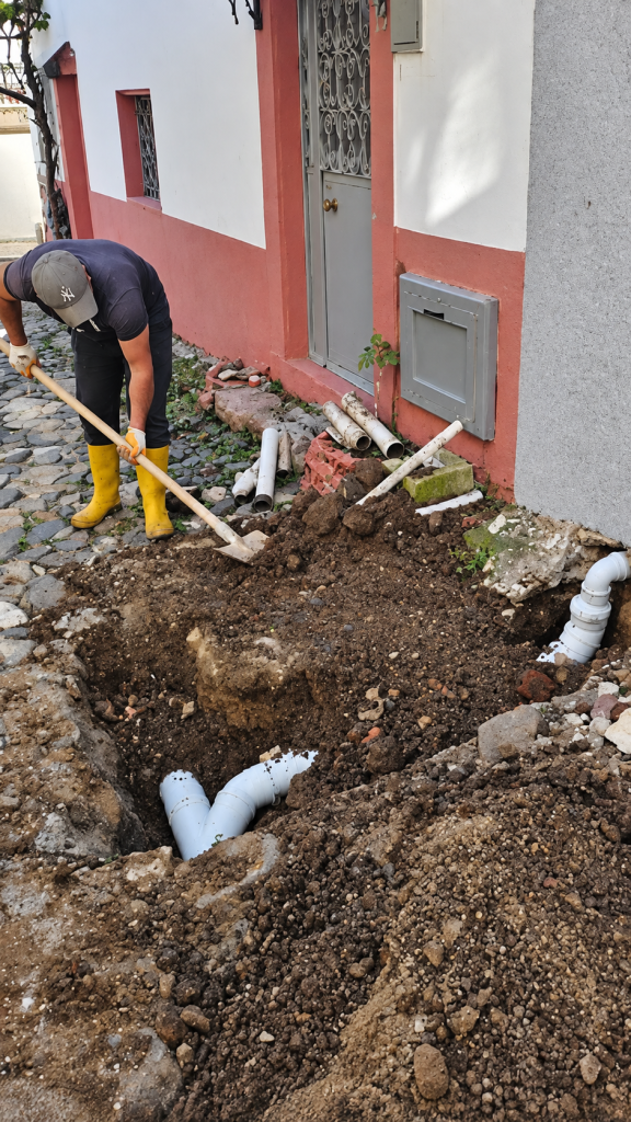 Ayvalık sokaklarında binaların dış mekan kanalizasyon tıkanıklığını gidermek için yapılan altyapı kazı ve yeni pimaş boru döşeme çalışması.